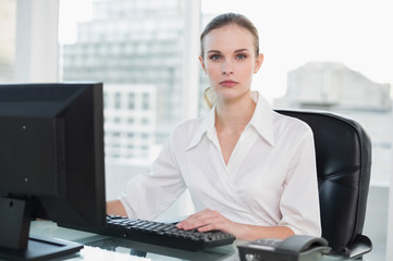 Serious businesswoman sitting at desk looking at camera