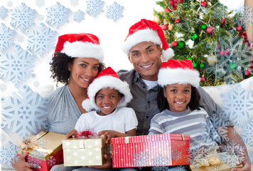 Obraz na płótnie Canvas Composite image of family holding Christmas presents against snowflake frame