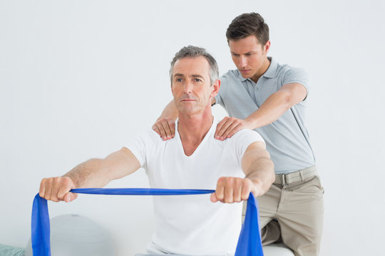 Therapist massaging mans shoulder in gym hospital