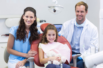 Portrait of dentist with young patient and her mother