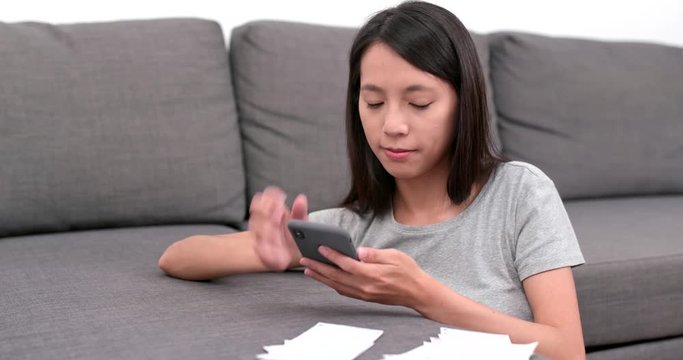 Woman use of mobile phone for record the daily expenditure at home