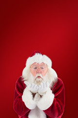 Santa Claus blows something away against red background