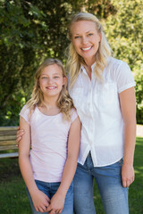 Obraz premium Mother with arm around daughter standing in park
