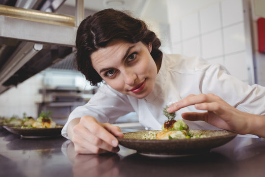 Female chef examining appetizer plate at order station