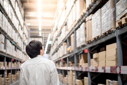 Young Asian man standing in warehouse choosing what to buy, shopping warehousing concept