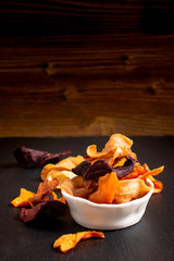 Food concept assort of vegetable chips on black slate plate