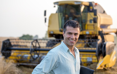 Engineer with laptop and combine harvester