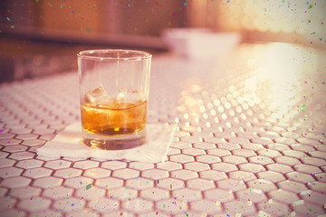 Glass of whisky on bar counter against flying colours
