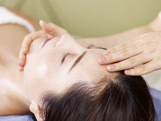 Fototapeta na wymiar young asian woman receiving face massage in spa salon
