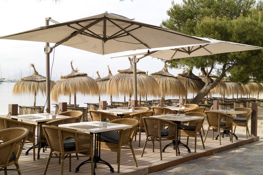 Porto Pollensa, Mallorca, Spain. 2018. Beachside tables and chairs set for breakfast in an early morning light.