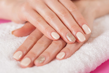 Young girls hands with cream color nails polish on fingers. Manicure and beauty hands concept. Close up, selective focus.