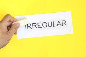 irregular is regular concept. Hand with eraser and card with word irregular