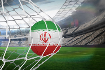 Football in iran colours at back of net against large football stadium with lights