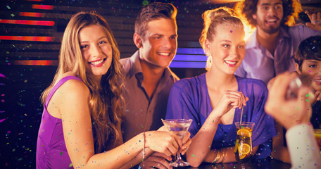 Group of friends having glass of cocktail at bar counter against flying colours