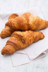 Tasty buttery croissants on old wooden table.