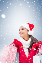 Festive brunette holding shopping bags against blue vignette