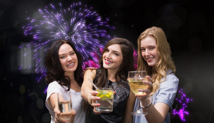 Friends with drinks against colourful fireworks exploding on black background