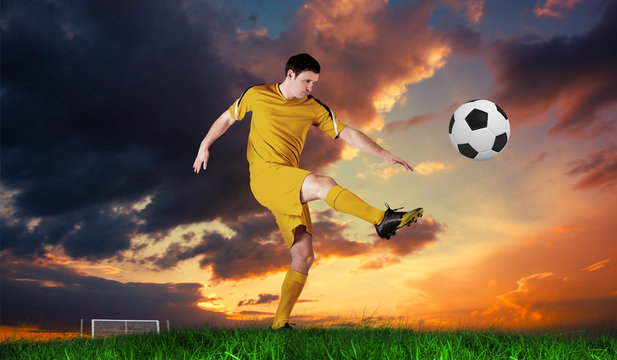 Football player in yellow kicking against green grass under blue sky © vectorfusionart