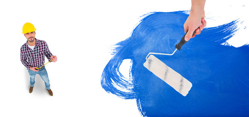 Handyman holding paint roller  against blue paint