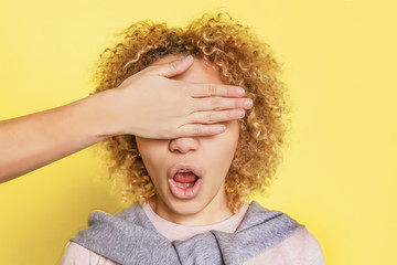 A picture of blonde girl with curly hair. She is wondering. The hand is closing her eyes. She can't...