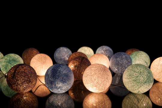 Colorful glowing balls on a black background. Glowing garland at night. Colorful circles on the background.