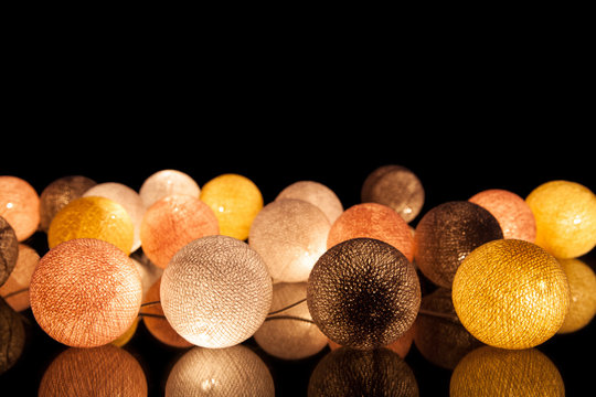 Colorful glowing balls on a black background. Glowing garland at night. Colorful circles on the background.