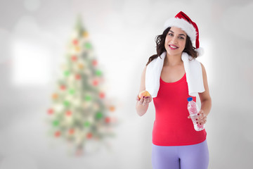 Festive fit brunette smiling at camera against blurry christmas tree in room