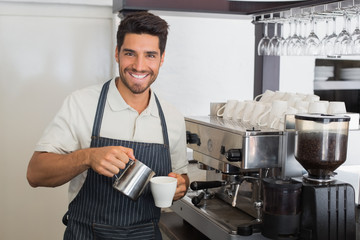 Waiter smiling and making cup of coffee at coffee shop