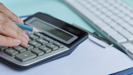 Close up Business man using calculator and laptop computer for calculating with finance paper, tax, accounting, Accountant concept.