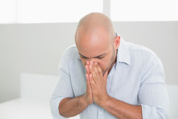 Sad casual man with hands to his face at home