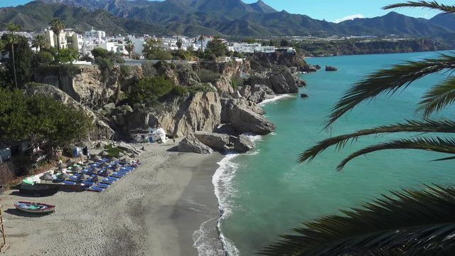 Playa Calahonda beach below the cliffs and town of Nerja with the Sierra de Tejeda, Almijara mountains in the background on the Costa del Sol in Spain.