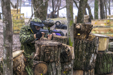 Obraz premium Paintball player takes aim, hides and shooting. Man wearing protective equipment