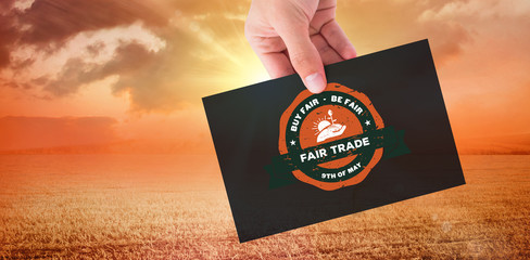 Hand showing card against sunrise over field