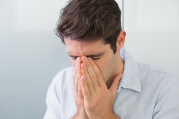 Sad casual young man with hands to his face