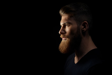 Silhouette of young confident handsome bearded man hipster wearing black knit hat. Studio shot on...