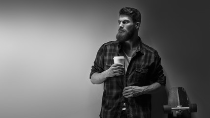 Fototapeta na wymiar Black and white photo of bearded stylish businessman with coffee in hand Handsome confident perfect hairstyle man having coffee indoor Male taking rest and drinking fresh morning coffee to go.