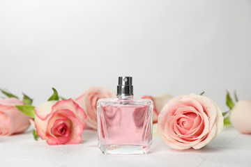 Perfume bottle and flowers on table against light background