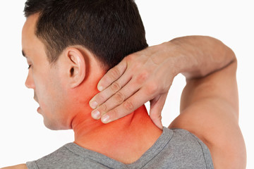 Fototapeta premium Young male massaging his back against a white background