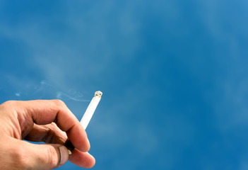 Male Hand Holding a Cigarette and Blue Sky