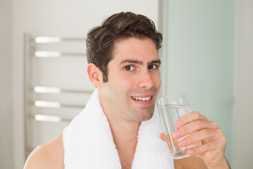 Man drinking water with towel around neck at home