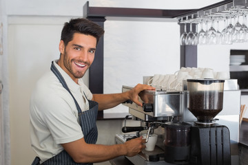 Smiling waiter making cup of coffee at coffee shop