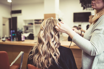 Beautiful hairstyle of young woman after dying hair and making highlights in hair salon. 