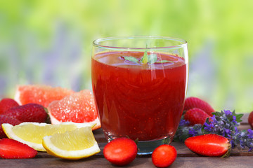 Dietary detox drink with strawberry, lemon and grapefruit in glass on wooden table. Picnic time, outdoor.