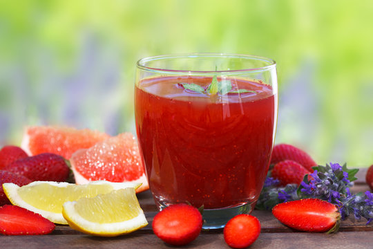 Dietary detox drink with strawberry, lemon and grapefruit in glass on wooden table. Picnic time, outdoor.