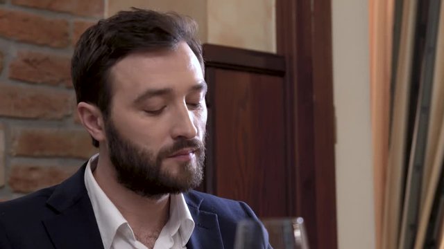 Closeup Of A Restaurant Guest. Face Of Bearded Man Eating The Dish And Wiping His Mouth With A Napkin.