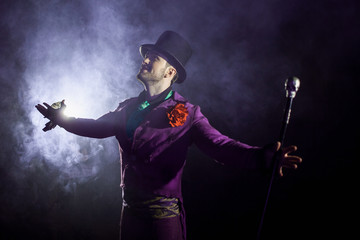 A young man in a purple suit standing out against the background of smoke. Showman, show begins