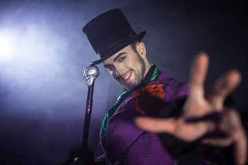 Attractive man in the cylinder. The hand gesture at the camera