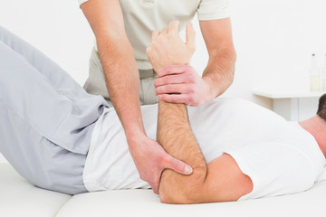 Fototapeta na wymiar Mid section of physiotherapist examining a mans hand