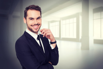 Stylish businessman smiling at camera against white room with windows