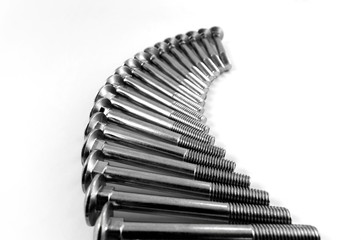 Metal screws with incomplete thread are laid out in a single row in the form of a curved arc for fixing parts.
